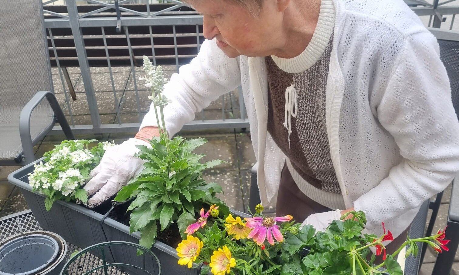 Bewohnerin bepflanzt einen Blumenkübel